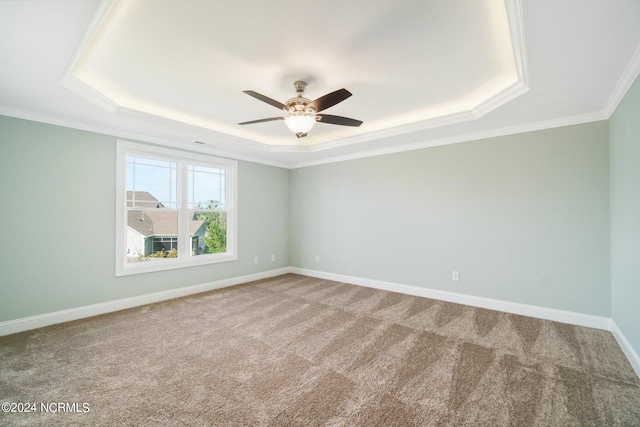 empty room featuring ornamental molding, carpet floors, ceiling fan, and a raised ceiling