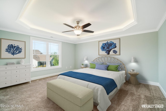 carpeted bedroom with ceiling fan, crown molding, and a tray ceiling