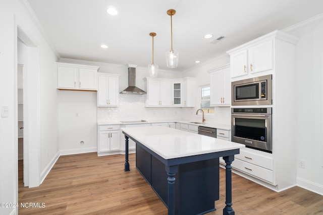 kitchen featuring appliances with stainless steel finishes, a center island, wall chimney exhaust hood, white cabinets, and a breakfast bar