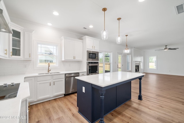 kitchen with appliances with stainless steel finishes, a wealth of natural light, and white cabinets