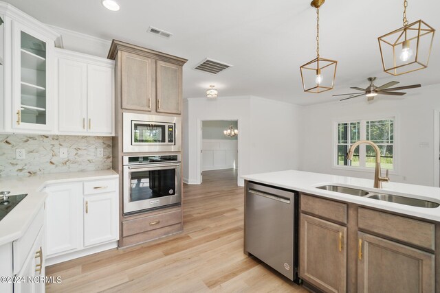 kitchen with ceiling fan with notable chandelier, white cabinets, appliances with stainless steel finishes, and sink