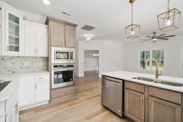 kitchen featuring visible vents, stainless steel appliances, a sink, and decorative light fixtures