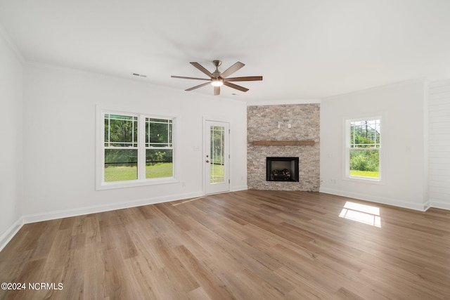 unfurnished living room with ceiling fan, plenty of natural light, light hardwood / wood-style floors, and a stone fireplace