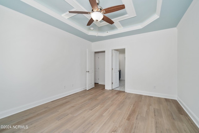 spare room featuring a ceiling fan, baseboards, light wood finished floors, ornamental molding, and a tray ceiling