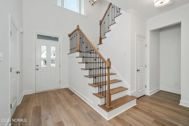 entrance foyer featuring crown molding, a healthy amount of sunlight, and light hardwood / wood-style flooring