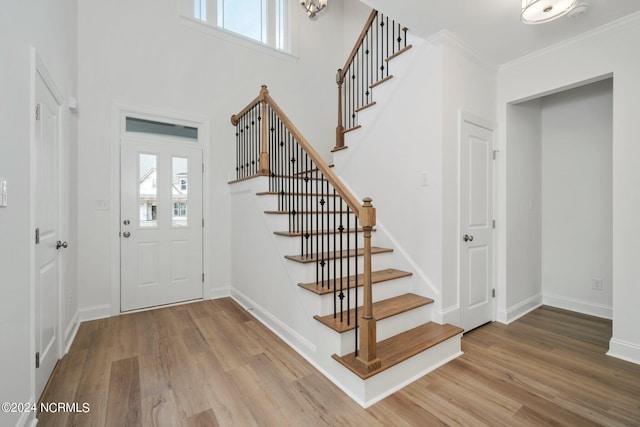 foyer with a healthy amount of sunlight, ornamental molding, and wood finished floors