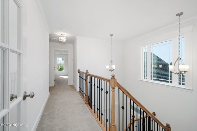 hall with light carpet, baseboards, ornamental molding, an upstairs landing, and a notable chandelier