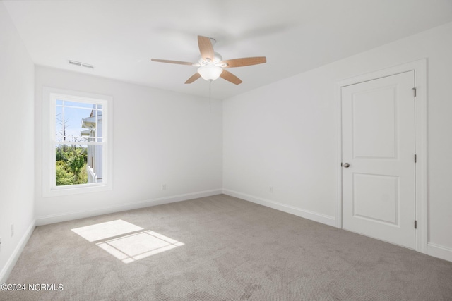 empty room featuring a ceiling fan, carpet, visible vents, and baseboards