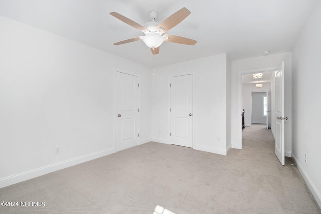 unfurnished bedroom with light carpet, baseboards, and a ceiling fan