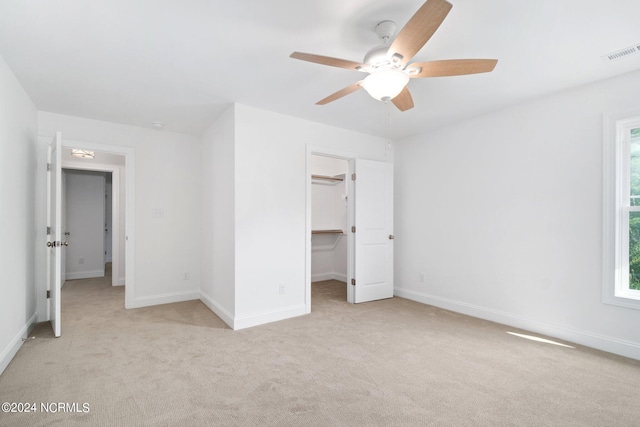 unfurnished bedroom featuring baseboards, a spacious closet, visible vents, and light colored carpet