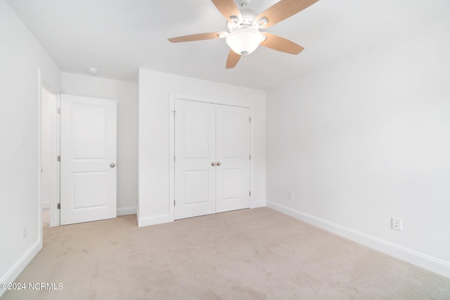 unfurnished bedroom featuring a closet, light colored carpet, and ceiling fan