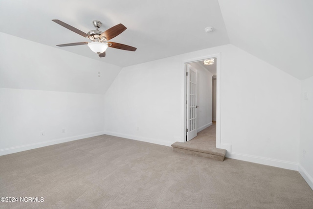 additional living space with vaulted ceiling, light colored carpet, and ceiling fan