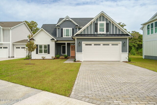 craftsman inspired home featuring an attached garage, brick siding, decorative driveway, and a front yard