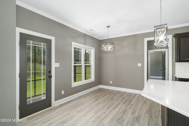 unfurnished dining area with a chandelier, light hardwood / wood-style flooring, and ornamental molding