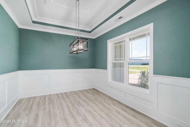 unfurnished room featuring an inviting chandelier, light hardwood / wood-style flooring, a tray ceiling, and ornamental molding