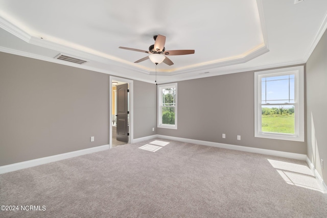 unfurnished room with light colored carpet, visible vents, baseboards, a raised ceiling, and crown molding