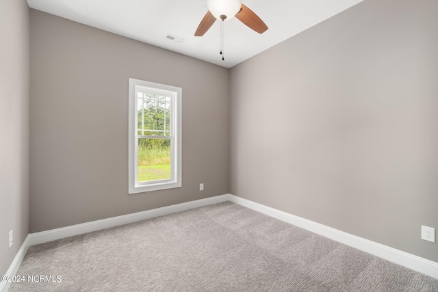 carpeted spare room featuring visible vents, baseboards, and a ceiling fan