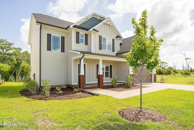 craftsman-style house featuring a shingled roof, a porch, decorative driveway, a front lawn, and board and batten siding