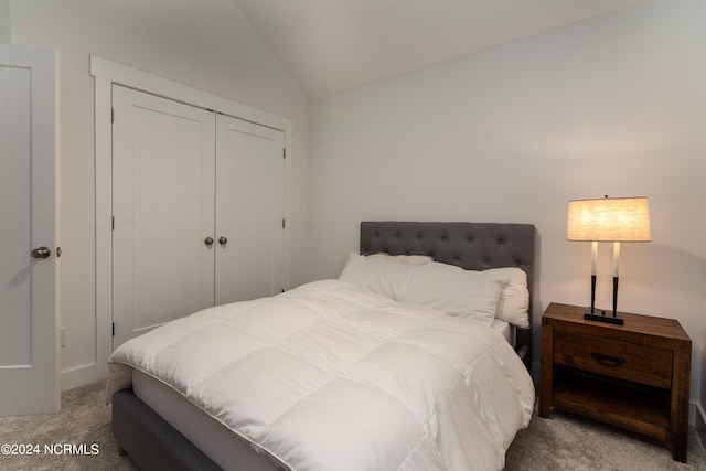 bedroom featuring a closet, lofted ceiling, and light carpet