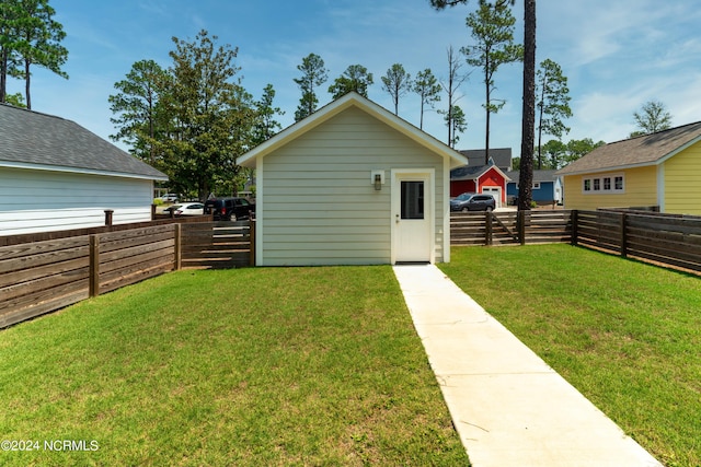 back of property featuring an outdoor structure and a lawn