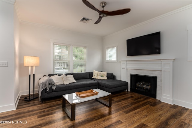 living room featuring dark hardwood / wood-style flooring, a brick fireplace, ornamental molding, and ceiling fan