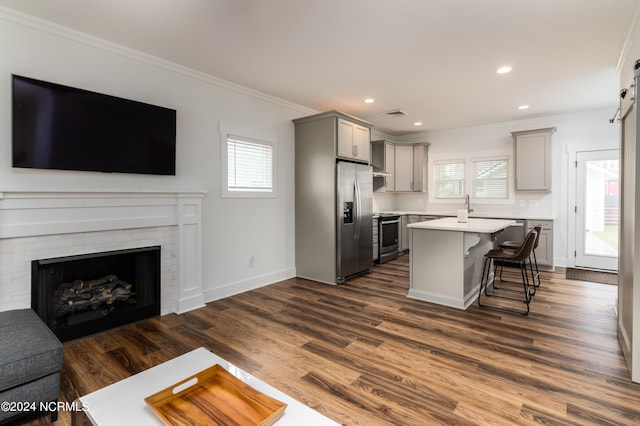 kitchen featuring gray cabinets, ornamental molding, a kitchen island, and a kitchen breakfast bar