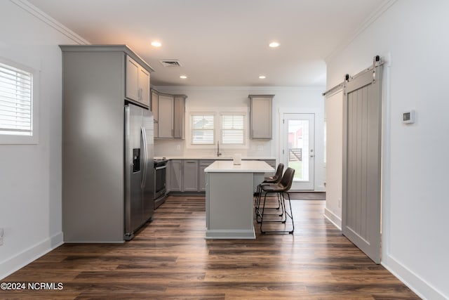 kitchen with gray cabinets, a breakfast bar, a center island, stainless steel appliances, and a barn door