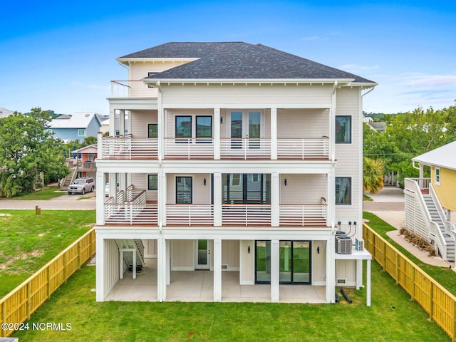 rear view of property with a balcony, a patio area, central AC, and a yard