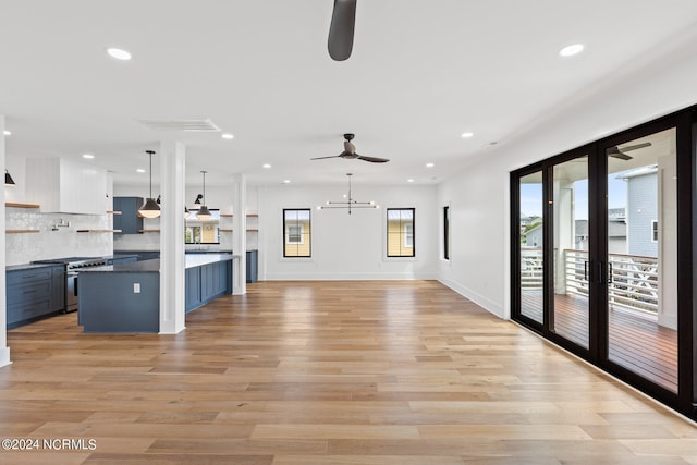 unfurnished living room with ceiling fan with notable chandelier, light hardwood / wood-style floors, and french doors