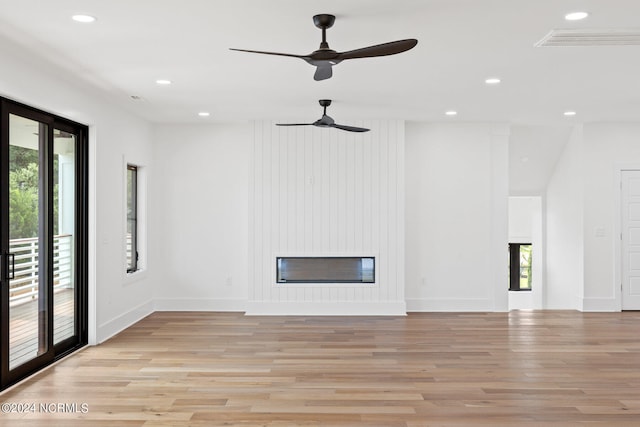 unfurnished living room featuring light hardwood / wood-style floors, a large fireplace, and ceiling fan