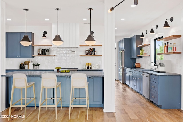 kitchen with blue cabinets, light hardwood / wood-style flooring, stainless steel appliances, and backsplash