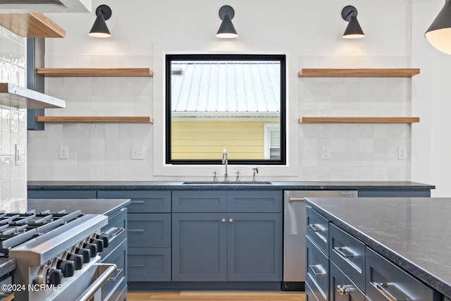 kitchen featuring range with two ovens, tasteful backsplash, dark stone counters, sink, and light wood-type flooring