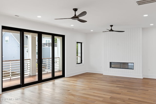 unfurnished room featuring a fireplace, ceiling fan, and light hardwood / wood-style floors