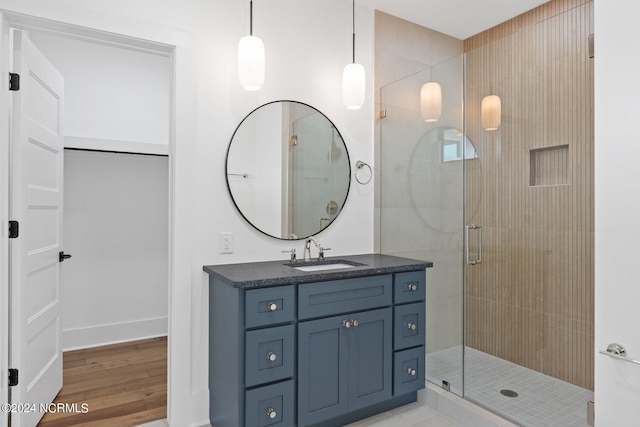 bathroom with a shower with shower door, vanity, and wood-type flooring