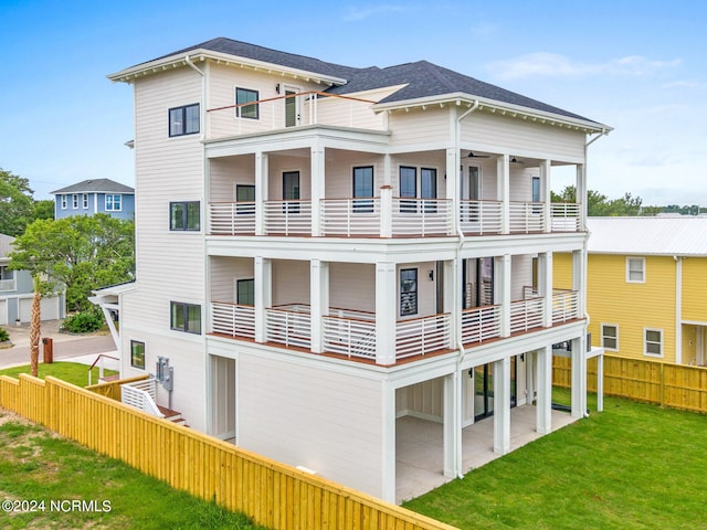 rear view of house featuring a balcony, a lawn, and a patio area