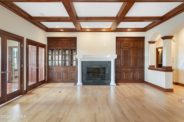 unfurnished living room featuring a tiled fireplace, coffered ceiling, and light hardwood / wood-style flooring