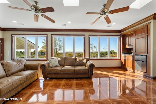 living room featuring ornamental molding, tile patterned floors, a skylight, and ceiling fan