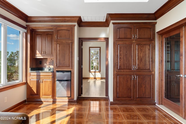 kitchen with crown molding, a healthy amount of sunlight, and stainless steel refrigerator