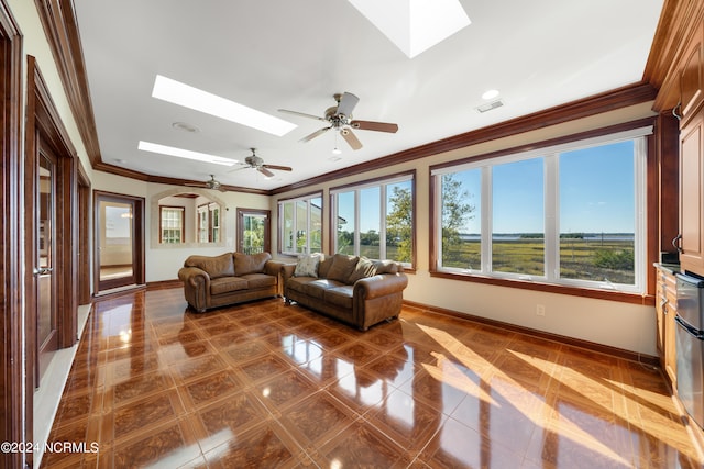 living room featuring ornamental molding, tile patterned floors, a skylight, and ceiling fan