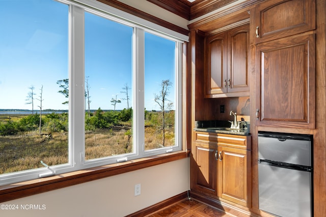 bar featuring crown molding, sink, and stainless steel refrigerator