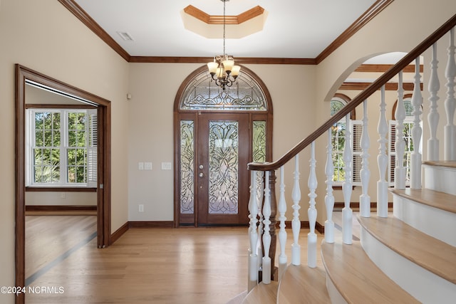 foyer featuring ornamental molding, light hardwood / wood-style flooring, and an inviting chandelier