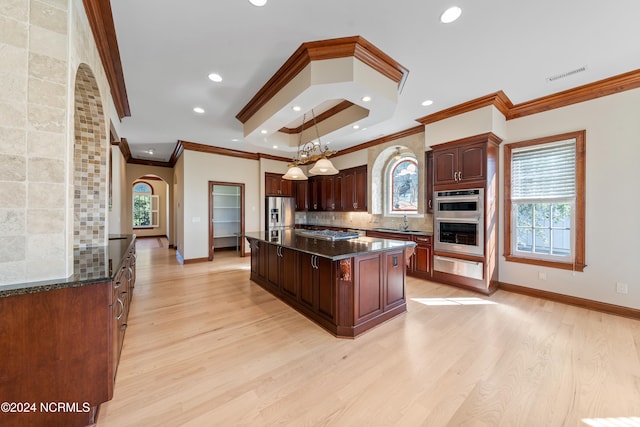 kitchen with a kitchen island, stainless steel appliances, pendant lighting, light wood-type flooring, and tasteful backsplash