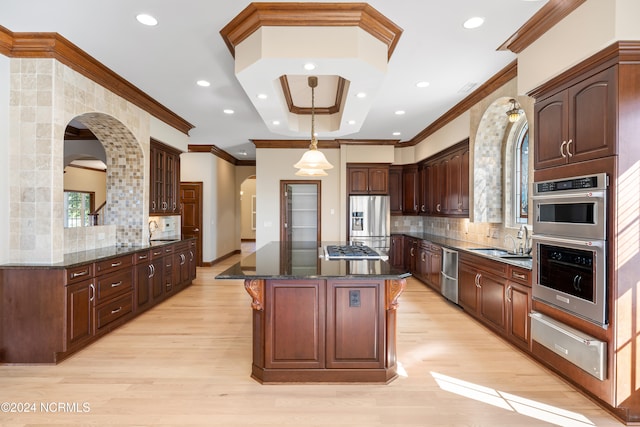 kitchen featuring tasteful backsplash, appliances with stainless steel finishes, light wood-type flooring, and a kitchen island