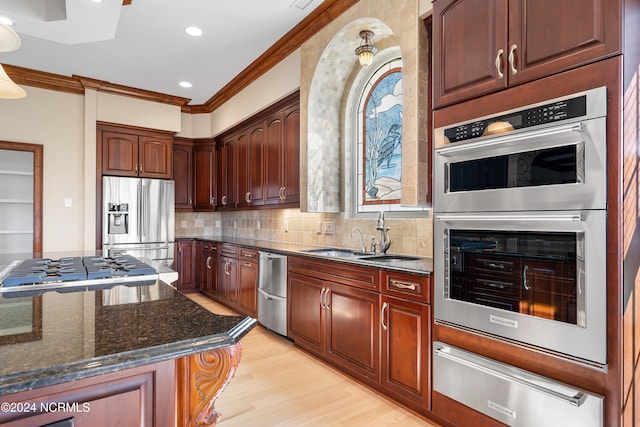 kitchen with decorative backsplash, light hardwood / wood-style flooring, dark stone countertops, sink, and stainless steel appliances