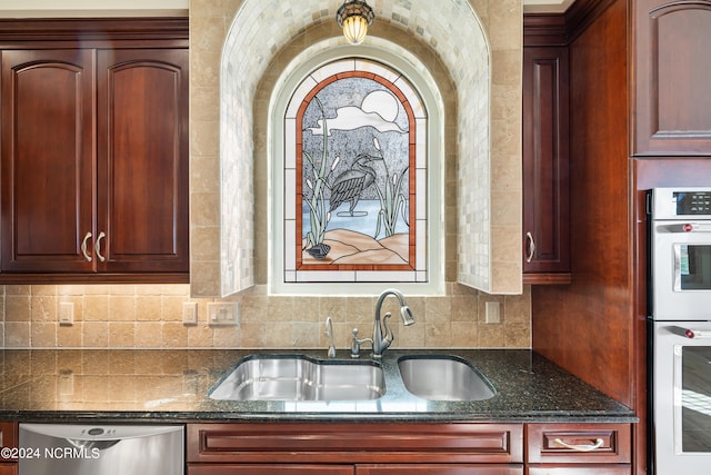 kitchen featuring dishwasher, backsplash, dark stone countertops, sink, and white double oven