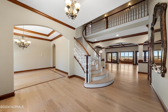 entryway featuring light hardwood / wood-style floors, ornamental molding, and an inviting chandelier