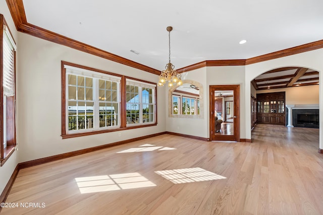 unfurnished dining area with a wealth of natural light, coffered ceiling, an inviting chandelier, and light hardwood / wood-style floors