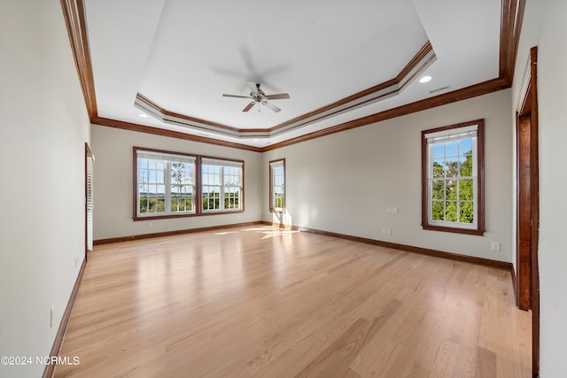 empty room with ornamental molding, a tray ceiling, light wood-type flooring, and ceiling fan