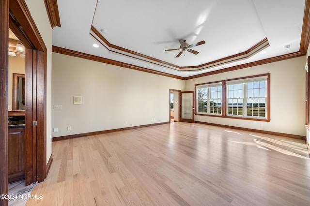 unfurnished room with ornamental molding, a tray ceiling, light hardwood / wood-style floors, and ceiling fan