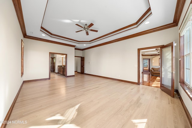 unfurnished room with light hardwood / wood-style floors, ornamental molding, a tray ceiling, and ceiling fan